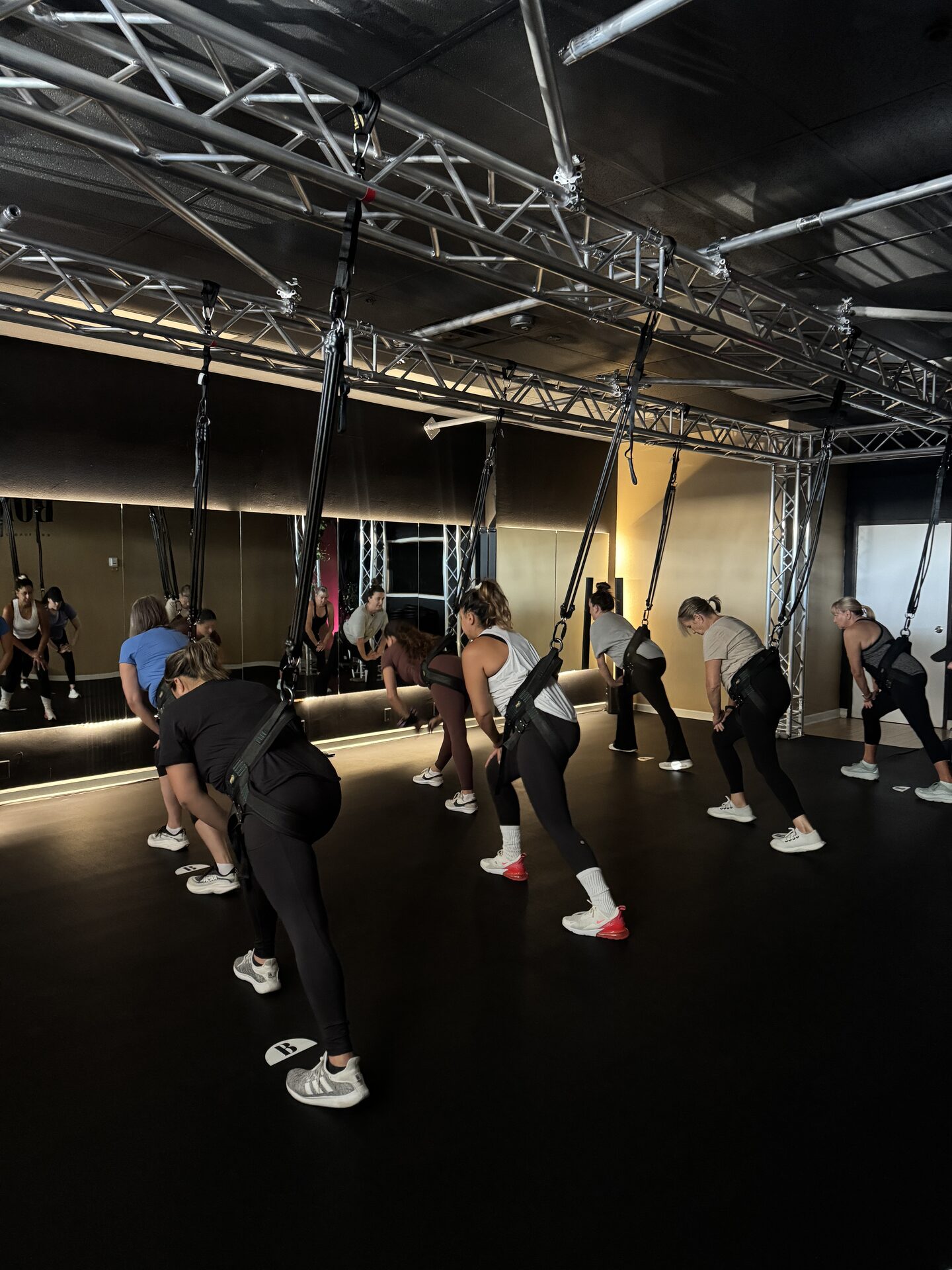 Students in bungee harnesses holding a resistance pose during a class at BUNGE Fitness in Huntington Beach
