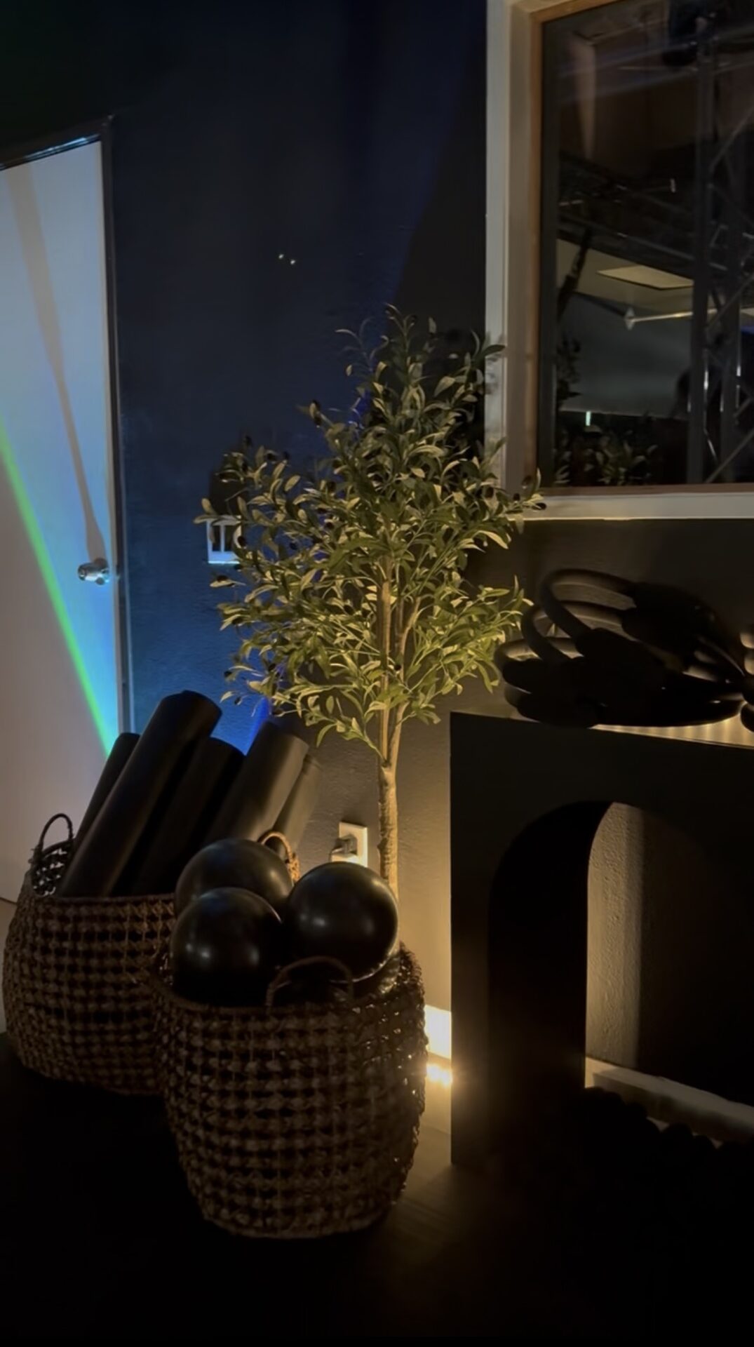 Studio decor details at BUNGE Fitness — olive tree, baskets and hand weights in warm light