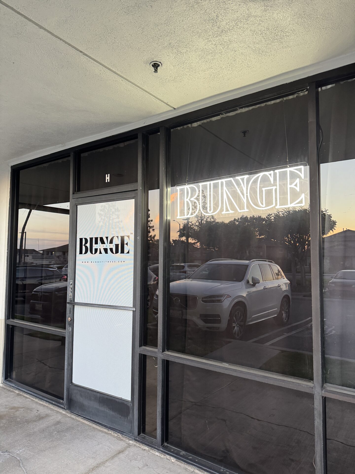 The BUNGE Fitness storefront at dusk with its neon sign on Gothard Street in Huntington Beach